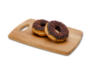 two ring doughnuts with black icing and halloween sprinkles on a wooden chopping board